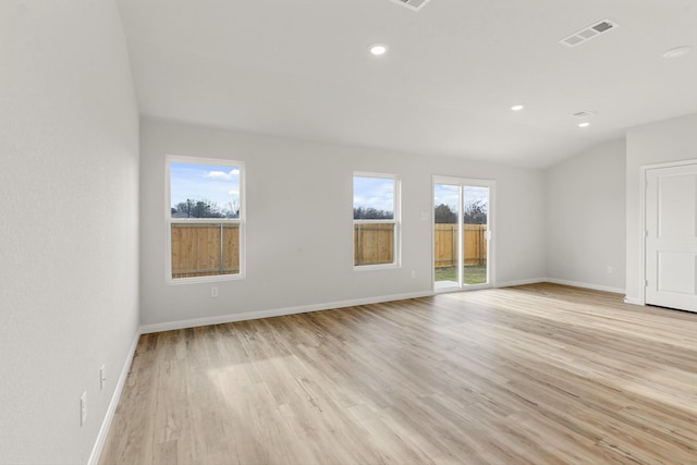 unfurnished room featuring lofted ceiling and light hardwood / wood-style flooring