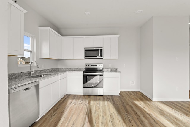 kitchen featuring white cabinetry, sink, light stone counters, and appliances with stainless steel finishes