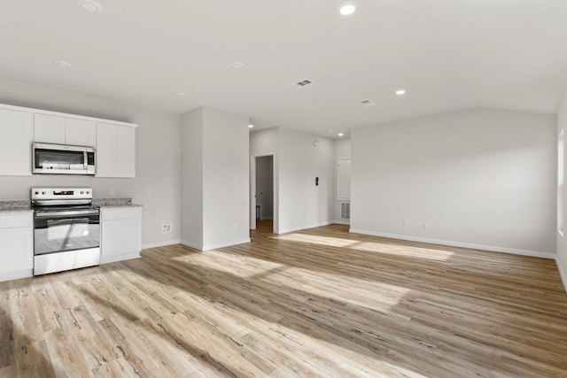 kitchen featuring light stone countertops, white cabinetry, appliances with stainless steel finishes, and light wood-type flooring