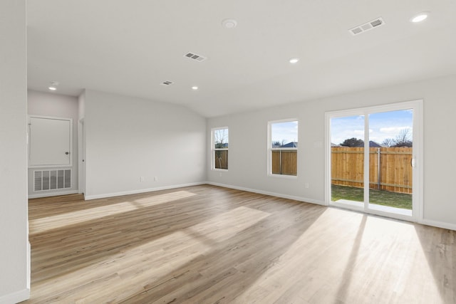 empty room with lofted ceiling, plenty of natural light, and light wood-type flooring