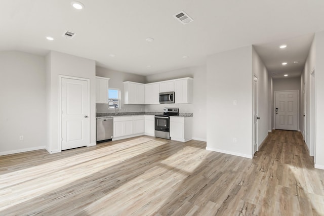 kitchen with sink, light wood-type flooring, white cabinets, and appliances with stainless steel finishes