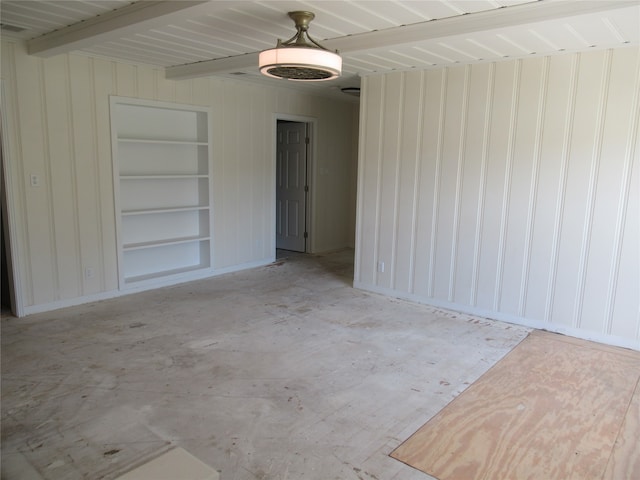 empty room with beamed ceiling and built in shelves