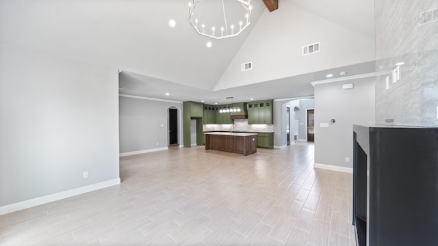 unfurnished living room featuring sink, an inviting chandelier, light tile patterned floors, and high vaulted ceiling