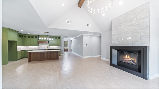 kitchen with a center island with sink, sink, a fireplace, premium range hood, and green cabinetry