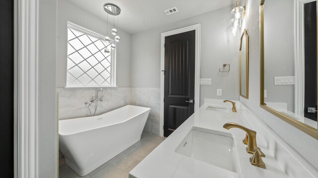 bathroom with a bathtub, tile patterned flooring, tile walls, and double vanity