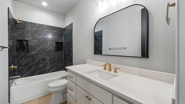 full bathroom with vanity, hardwood / wood-style flooring, tiled shower / bath, and toilet