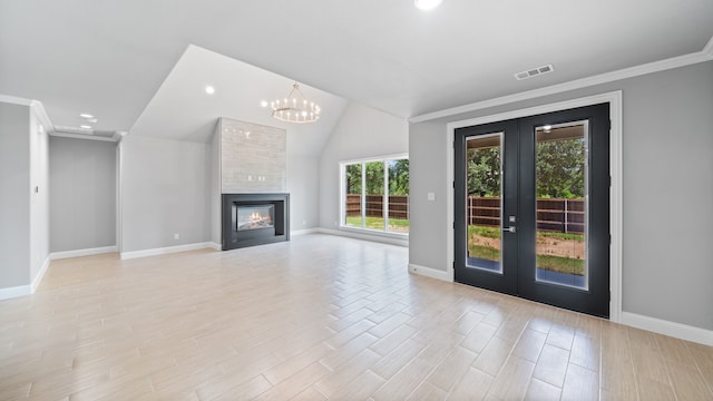 unfurnished living room featuring lofted ceiling, crown molding, french doors, a chandelier, and a fireplace