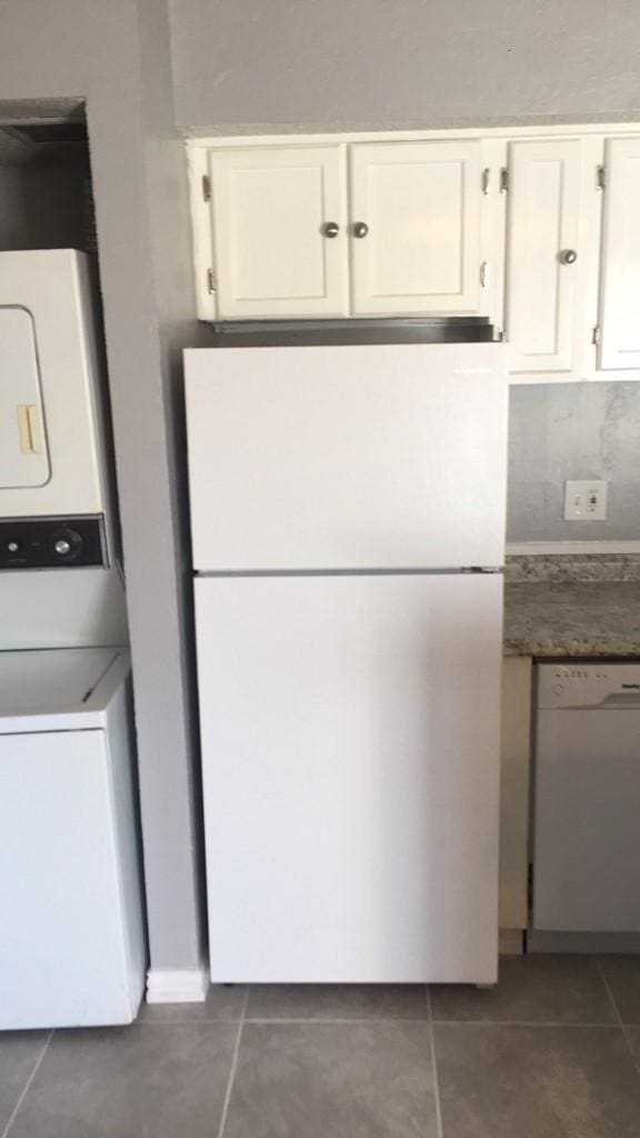 kitchen with white cabinetry, dark tile patterned floors, and white appliances