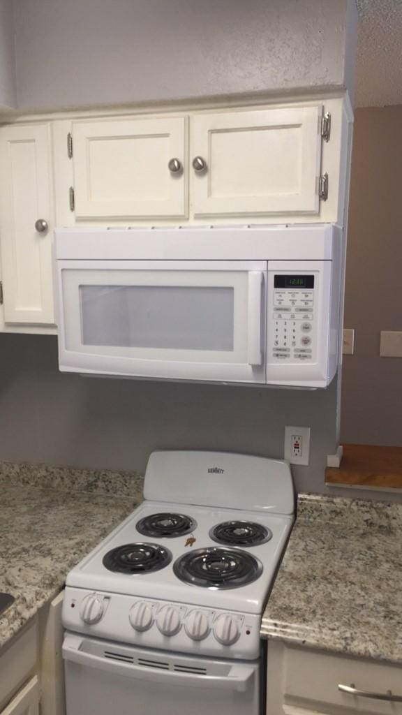 kitchen featuring white cabinets, white appliances, and light stone counters