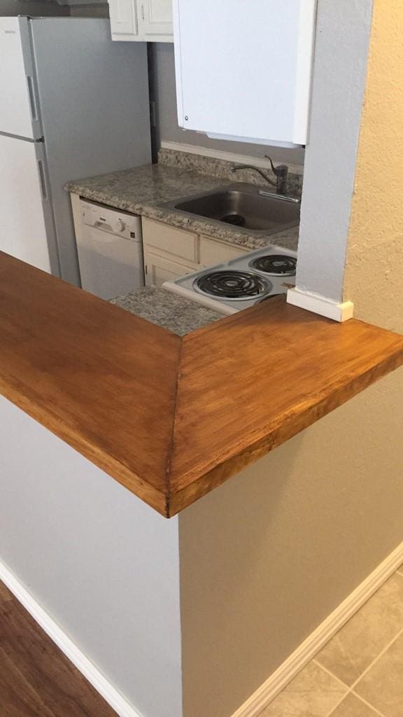 kitchen featuring dishwasher, range, sink, tile patterned flooring, and white cabinetry