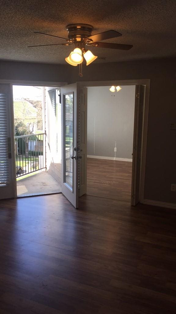 empty room with french doors, ceiling fan, dark hardwood / wood-style flooring, and a textured ceiling