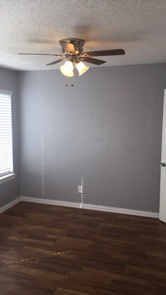 spare room featuring a textured ceiling, ceiling fan, and dark wood-type flooring