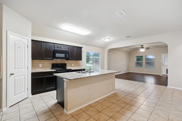 kitchen featuring plenty of natural light, tasteful backsplash, black appliances, and light hardwood / wood-style floors