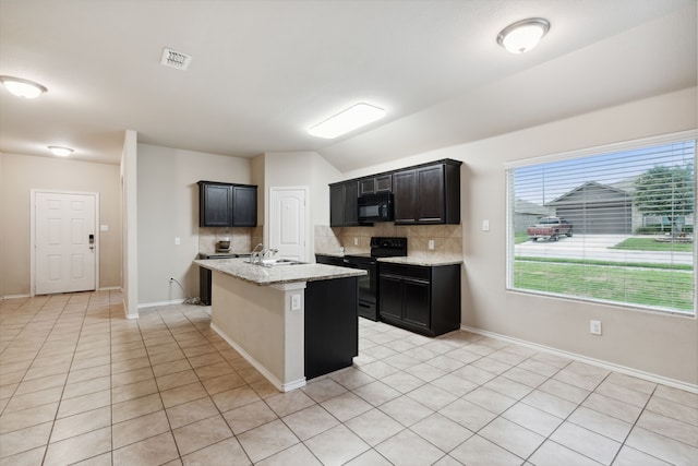 kitchen featuring decorative backsplash, black appliances, a kitchen island with sink, and light tile patterned floors