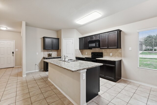 kitchen with sink, black appliances, decorative backsplash, and a kitchen island with sink