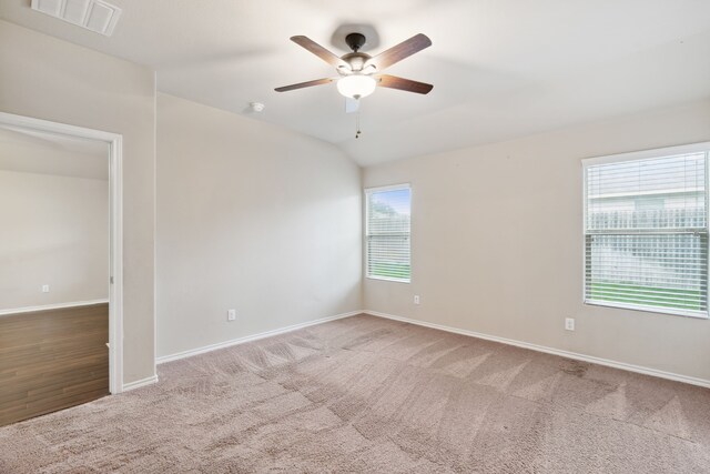 carpeted spare room featuring vaulted ceiling and ceiling fan