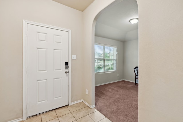 foyer entrance with vaulted ceiling and light carpet