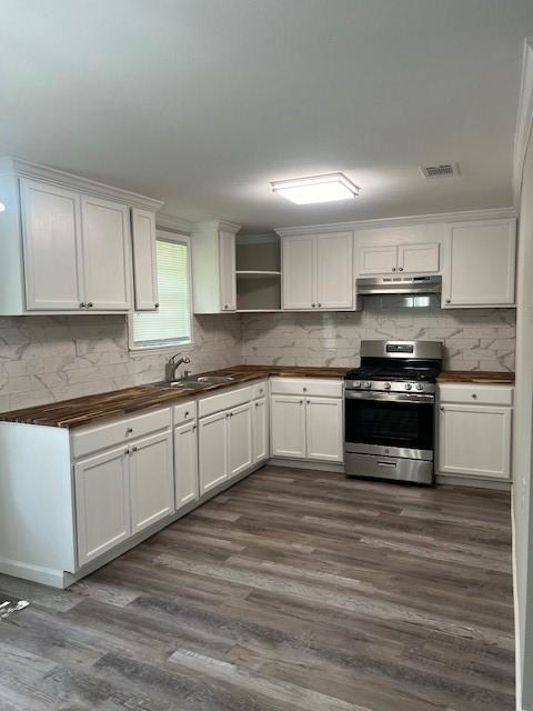 kitchen featuring tasteful backsplash, wooden counters, crown molding, dark hardwood / wood-style floors, and stainless steel range with gas stovetop