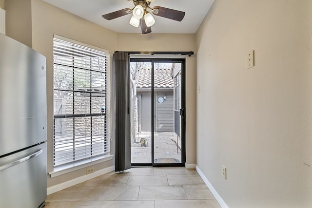 doorway with plenty of natural light, light tile patterned floors, and ceiling fan