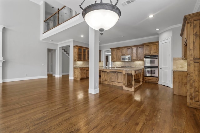 kitchen featuring a breakfast bar, backsplash, ornamental molding, appliances with stainless steel finishes, and dark hardwood / wood-style flooring