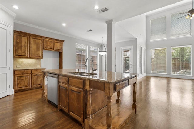 kitchen featuring backsplash, light stone counters, a kitchen island with sink, sink, and dishwasher