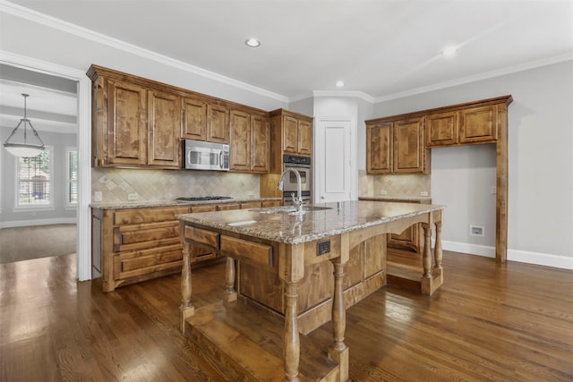 kitchen featuring light stone countertops, sink, a kitchen island with sink, stainless steel appliances, and decorative backsplash