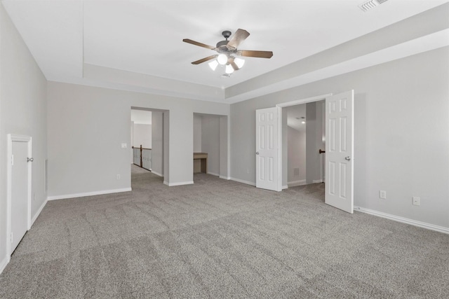 unfurnished bedroom featuring ceiling fan, a raised ceiling, light colored carpet, and connected bathroom