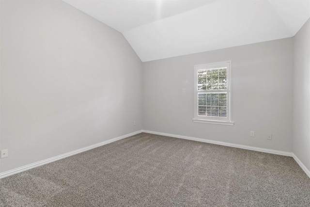 carpeted spare room featuring vaulted ceiling