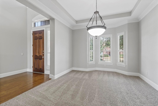 spare room featuring a raised ceiling, dark carpet, and ornamental molding