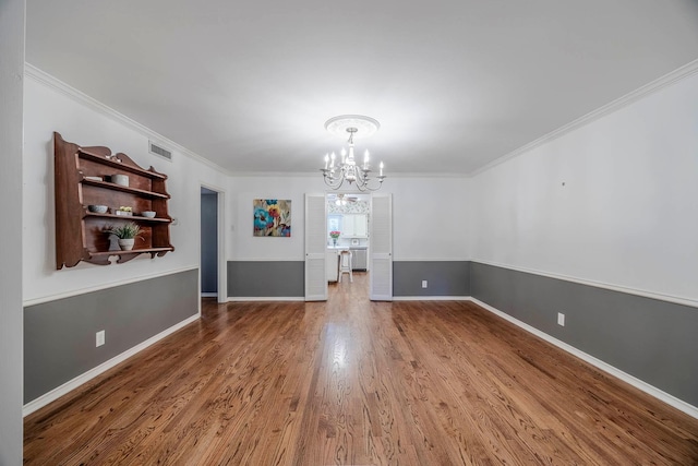 unfurnished dining area with ornamental molding, hardwood / wood-style floors, and a notable chandelier