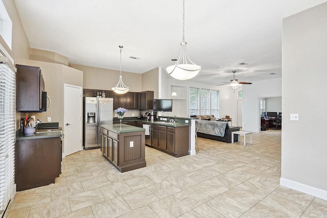 kitchen with ceiling fan, stainless steel appliances, hanging light fixtures, a center island, and dark brown cabinetry