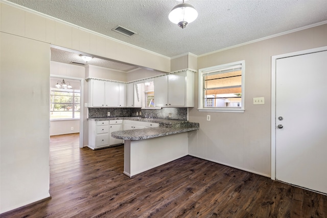 kitchen with crown molding, kitchen peninsula, white cabinets, dark wood-type flooring, and decorative backsplash