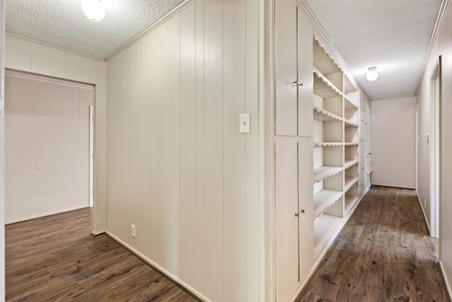 hall with dark hardwood / wood-style floors, ornamental molding, and a textured ceiling