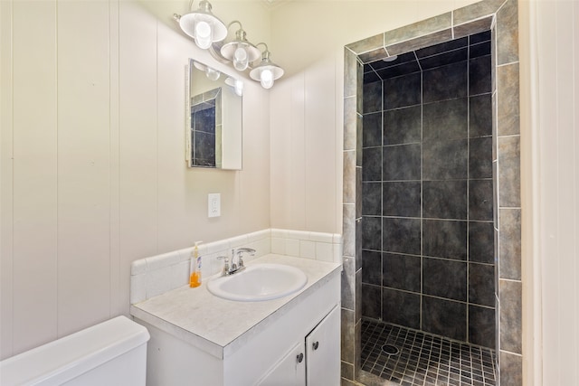 bathroom featuring tiled shower, toilet, and vanity