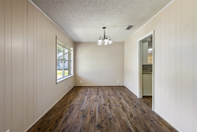 unfurnished dining area featuring an inviting chandelier, dark wood-type flooring, ornamental molding, and a textured ceiling