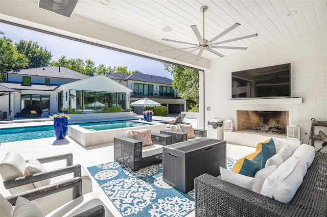 view of swimming pool with ceiling fan, a patio area, and an outdoor living space with a fireplace