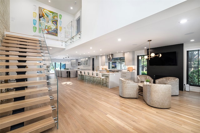 living room featuring a healthy amount of sunlight, sink, a chandelier, and light hardwood / wood-style floors