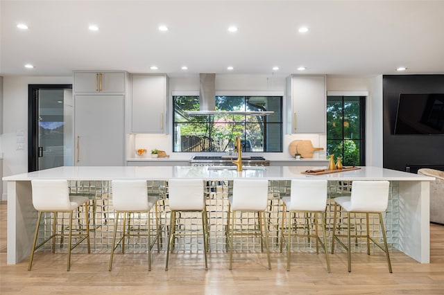 kitchen featuring extractor fan, a kitchen breakfast bar, a large island, and light hardwood / wood-style floors