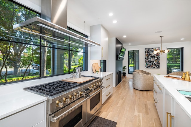 kitchen with pendant lighting, range with two ovens, and white cabinets