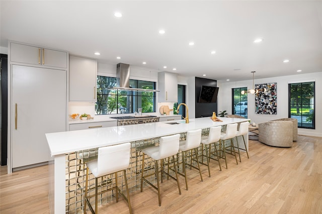 kitchen featuring light wood-type flooring, a breakfast bar area, pendant lighting, and a large island with sink