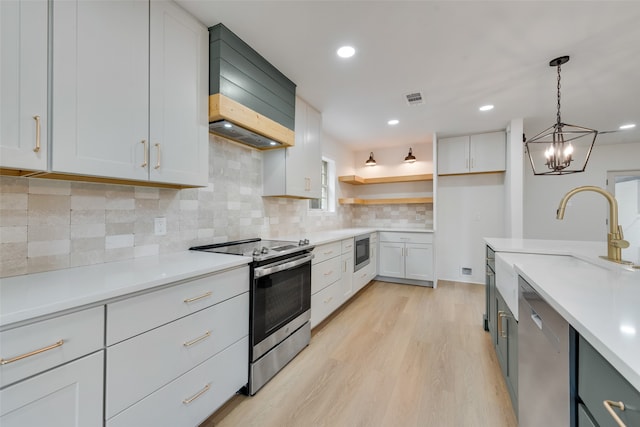 kitchen with decorative light fixtures, white cabinetry, light hardwood / wood-style flooring, and stainless steel appliances