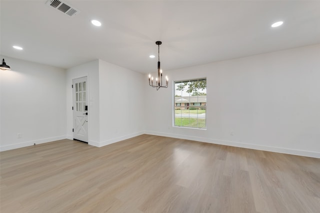 empty room with a notable chandelier and light wood-type flooring