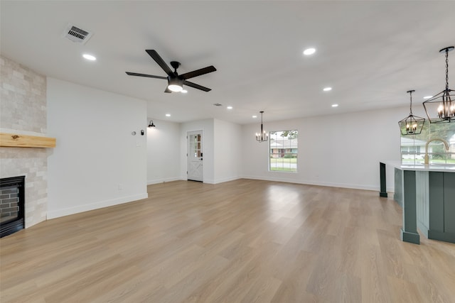 unfurnished living room featuring ceiling fan, sink, a stone fireplace, and light hardwood / wood-style floors