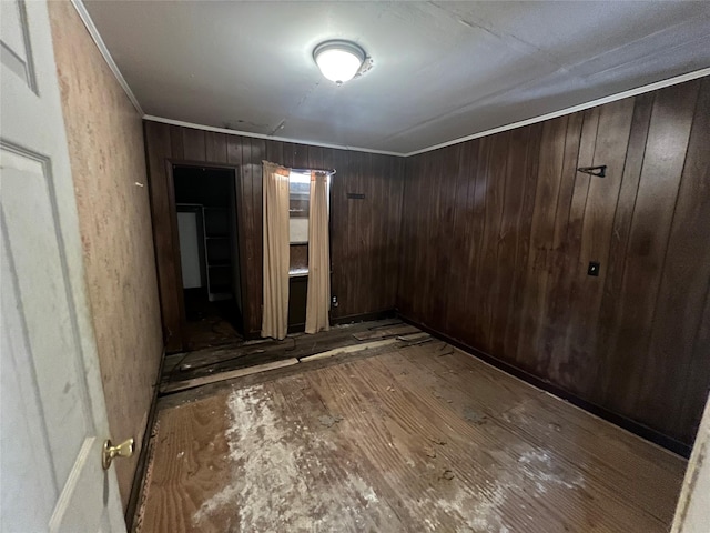 unfurnished room featuring wood walls and ornamental molding