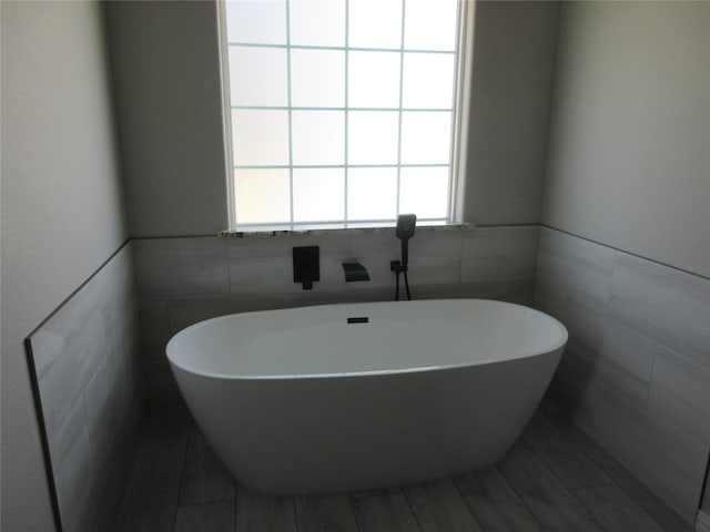 bathroom with a tub and tile walls