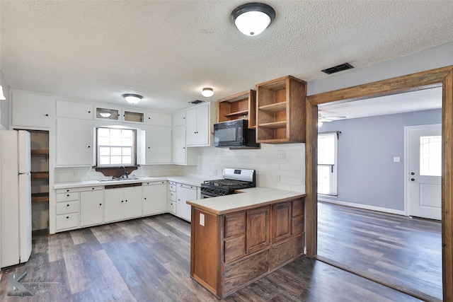 kitchen featuring sink, stainless steel range with gas stovetop, kitchen peninsula, white fridge, and white cabinets