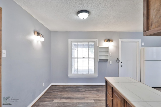 kitchen featuring tile countertops, dark hardwood / wood-style floors, a textured ceiling, and white refrigerator