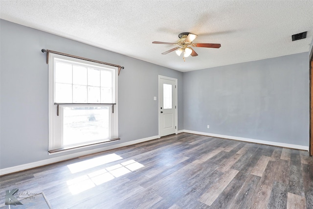 spare room featuring dark wood-type flooring, ceiling fan, and a textured ceiling