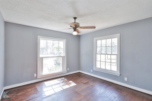 spare room with dark wood-type flooring, a wealth of natural light, a textured ceiling, and ceiling fan