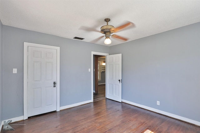 unfurnished bedroom featuring ceiling fan, dark wood-type flooring, and a textured ceiling